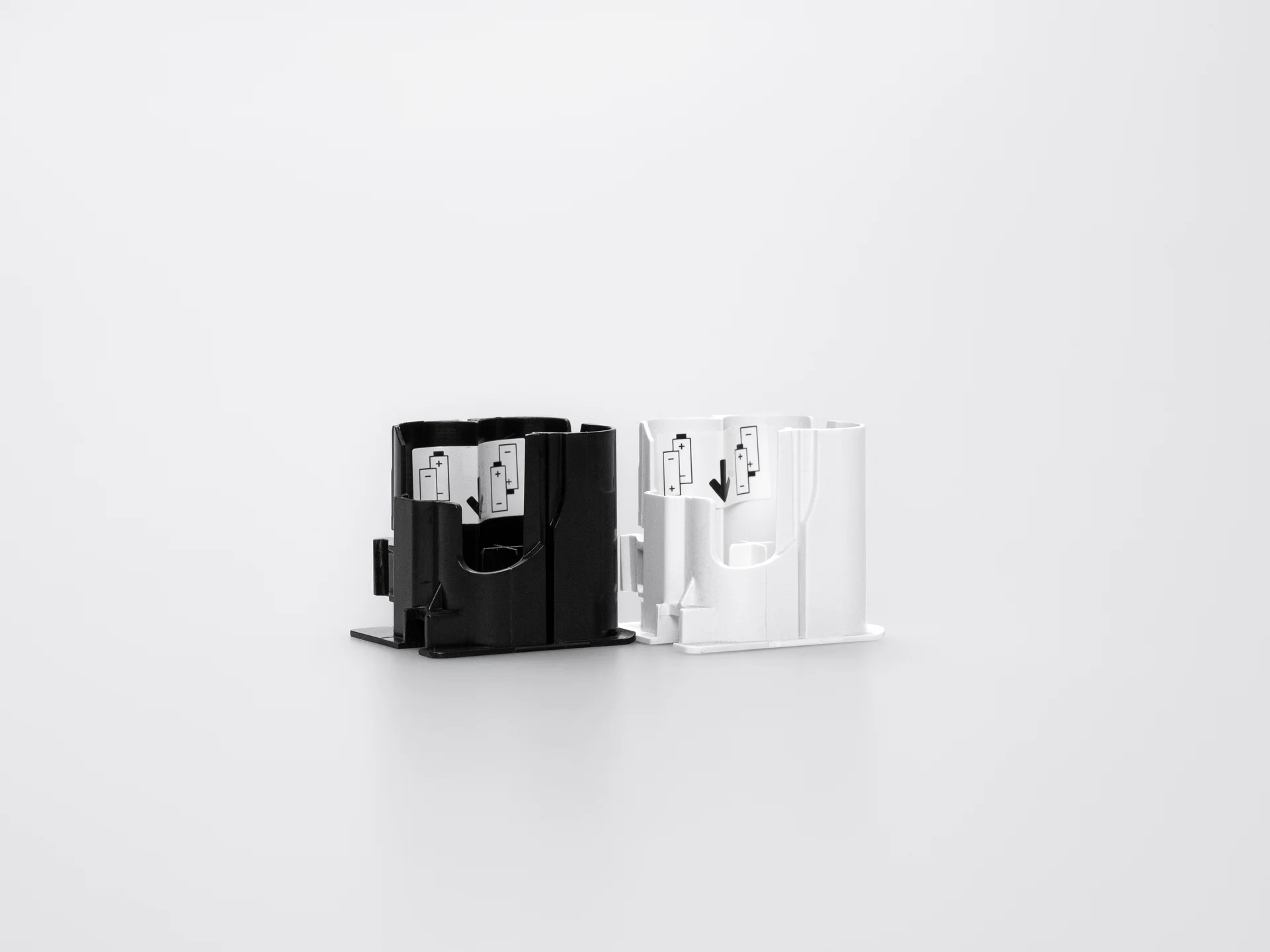 Black and white battery compartments for the Smart Lock, side by side with battery symbols visible.
