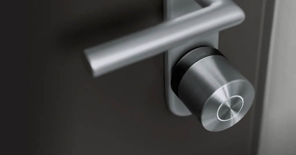 La Smart Lock Ultra con anello nero su una porta nera con ferramenta argentata.