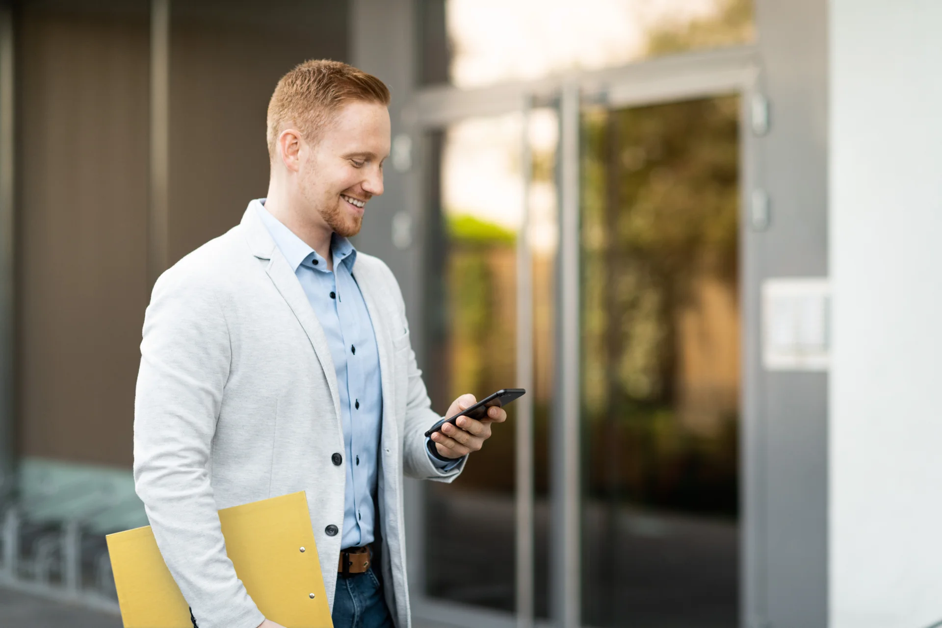Man smiles while unlocking a door with his smartphone.