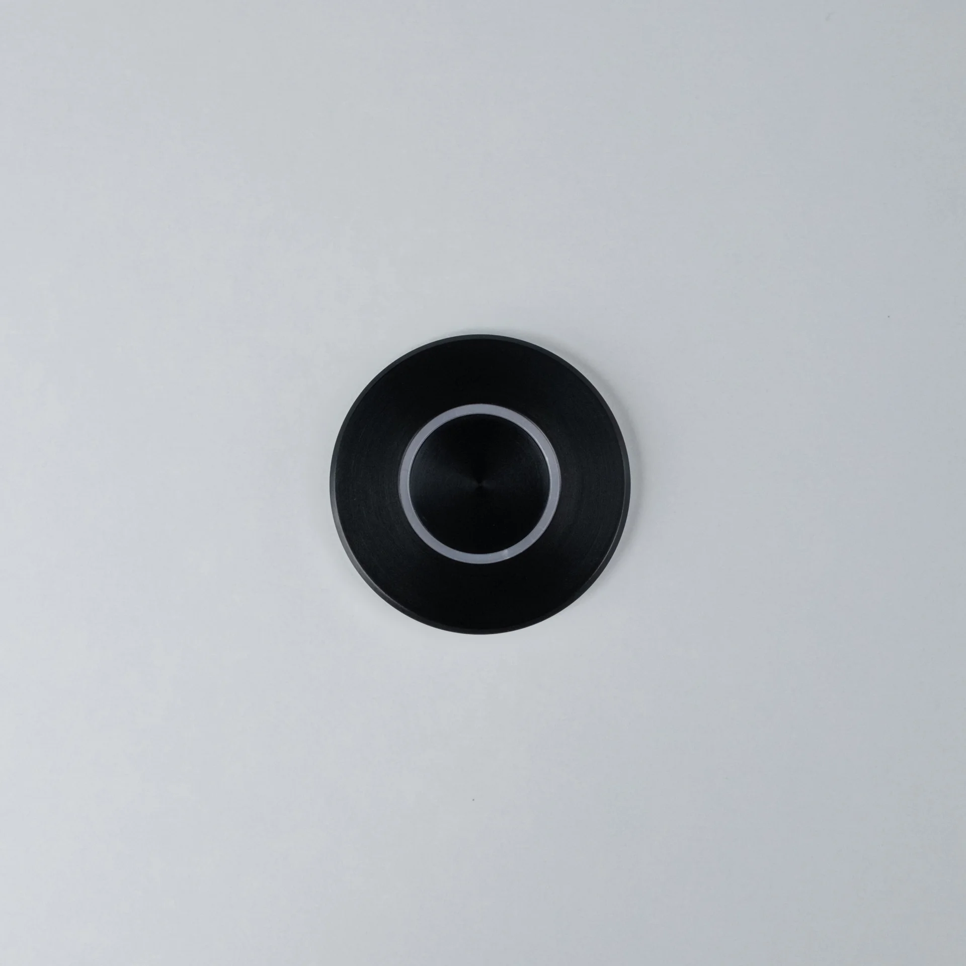 Black Nuki Button, round, integrated in a white door – turns a mechanical lock into a smart door.