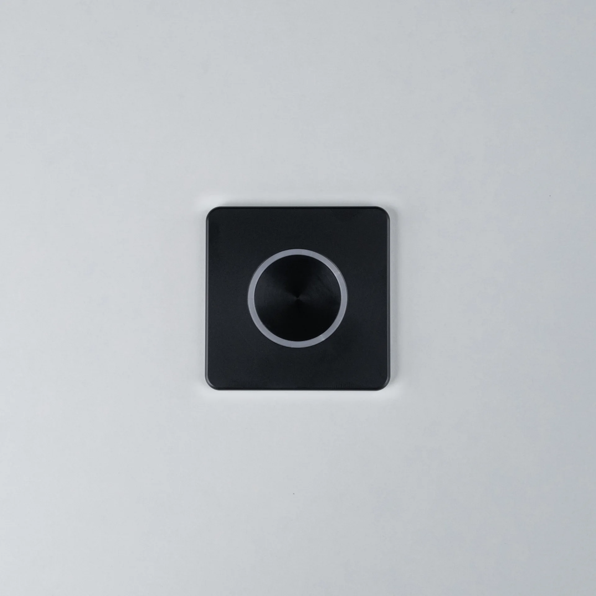 Black Nuki Button, square, integrated in a white door – turns a mechanical lock into a smart door.