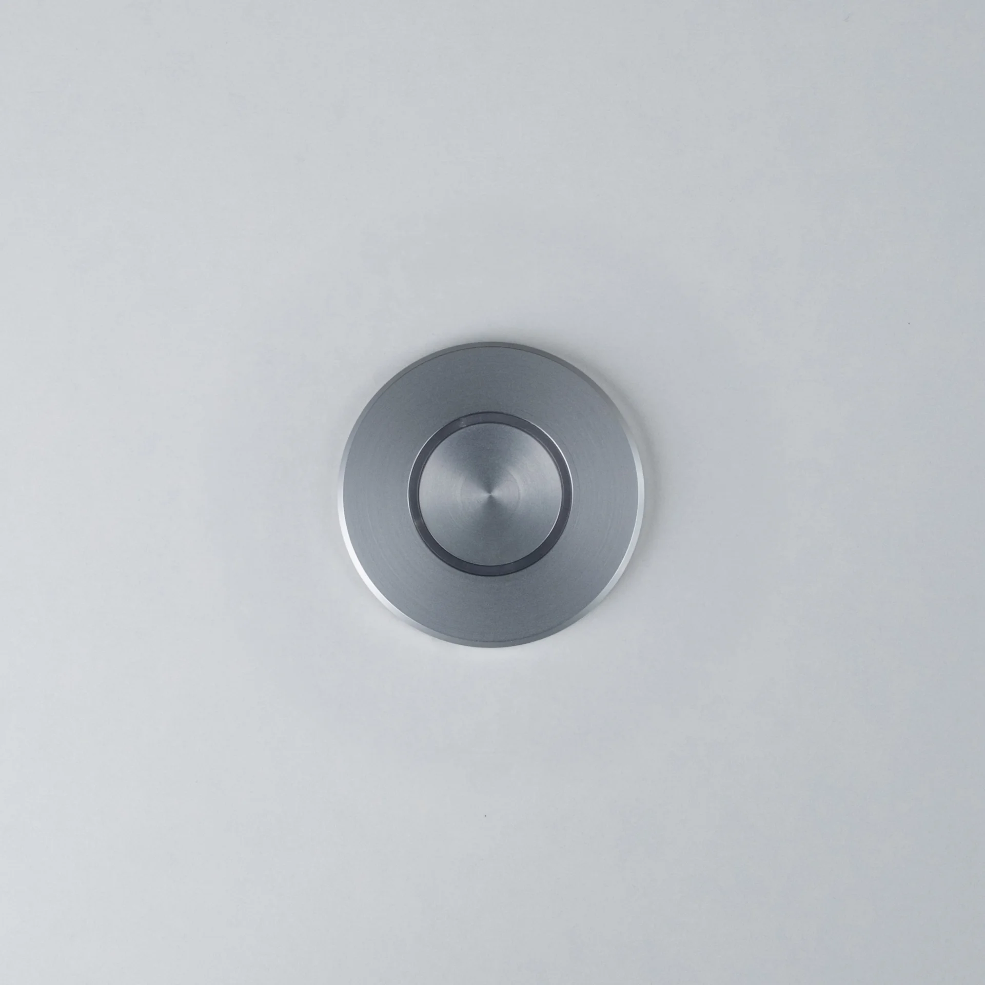 Silver Nuki Button, round, integrated in a white door – turns a mechanical lock into a smart door.