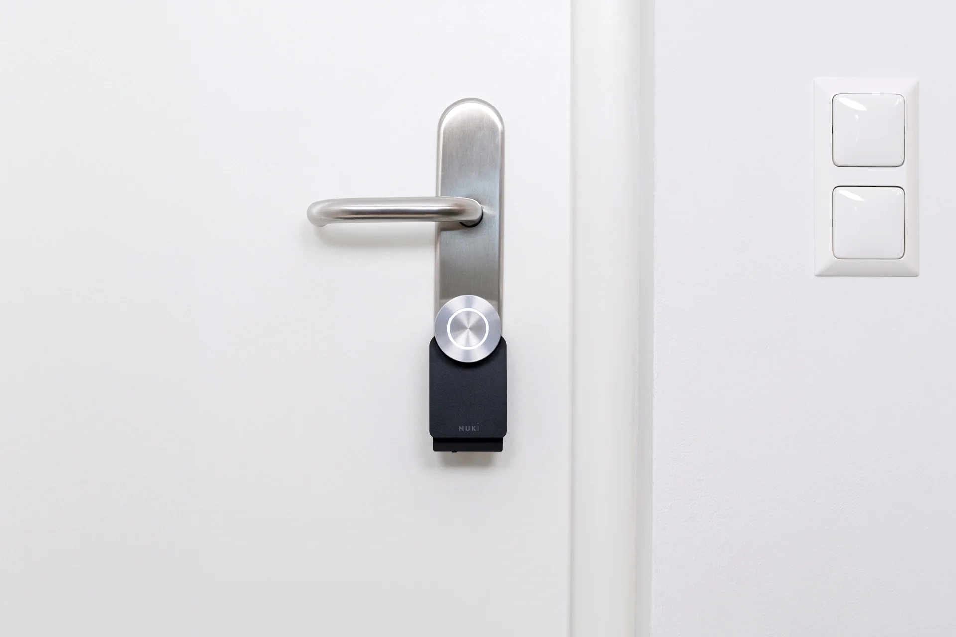 Nuki Smart Lock installed on a white door with stainless steel handle, ready for keyless smart access.