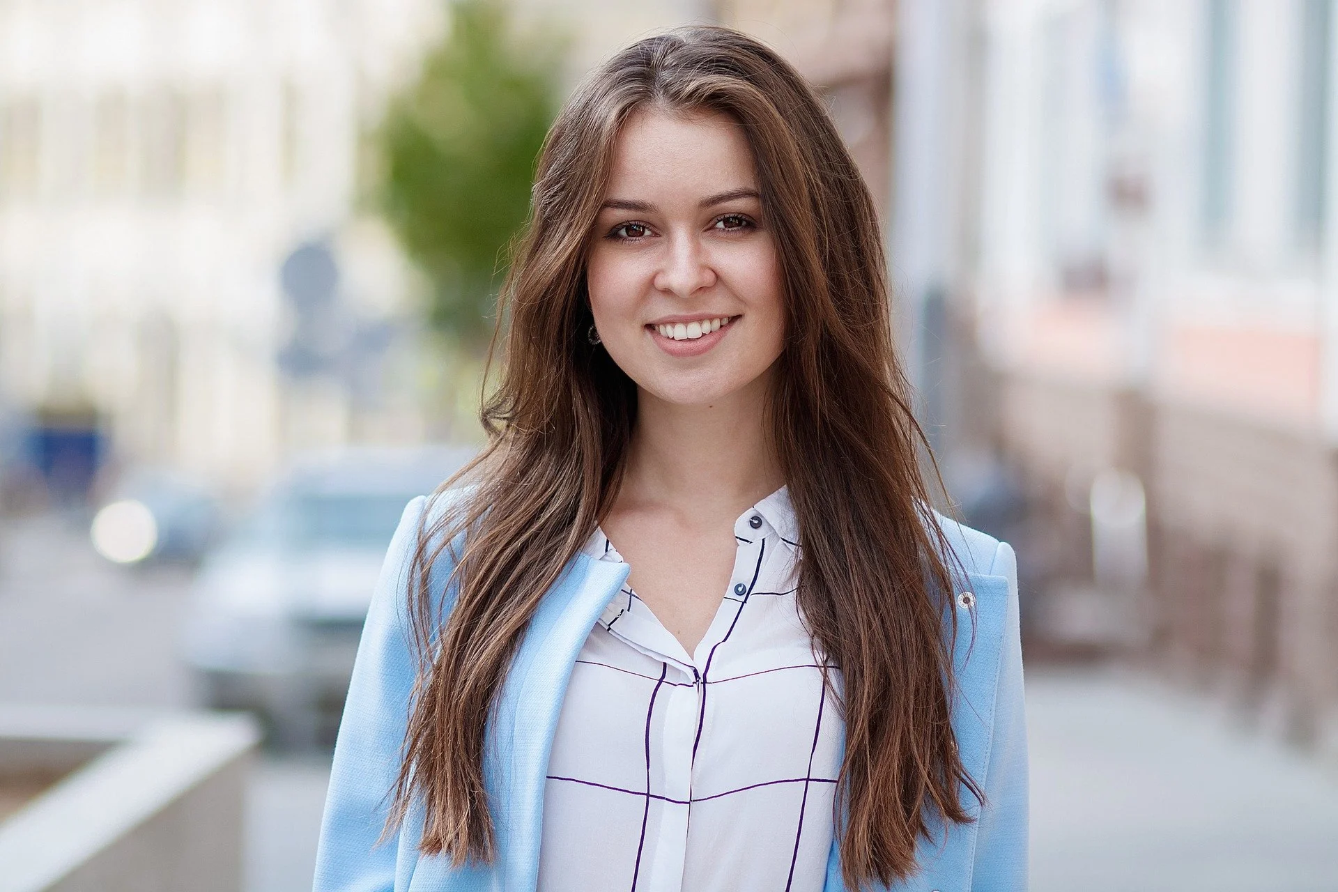 A woman stands in the streets and smiles.
