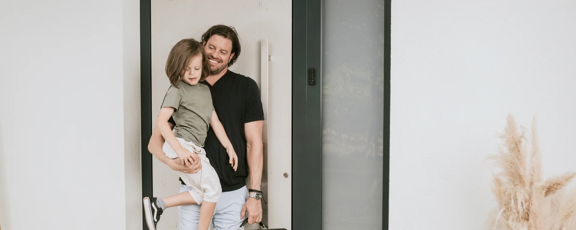 A father seen carrying his son and a bag when entering their home.