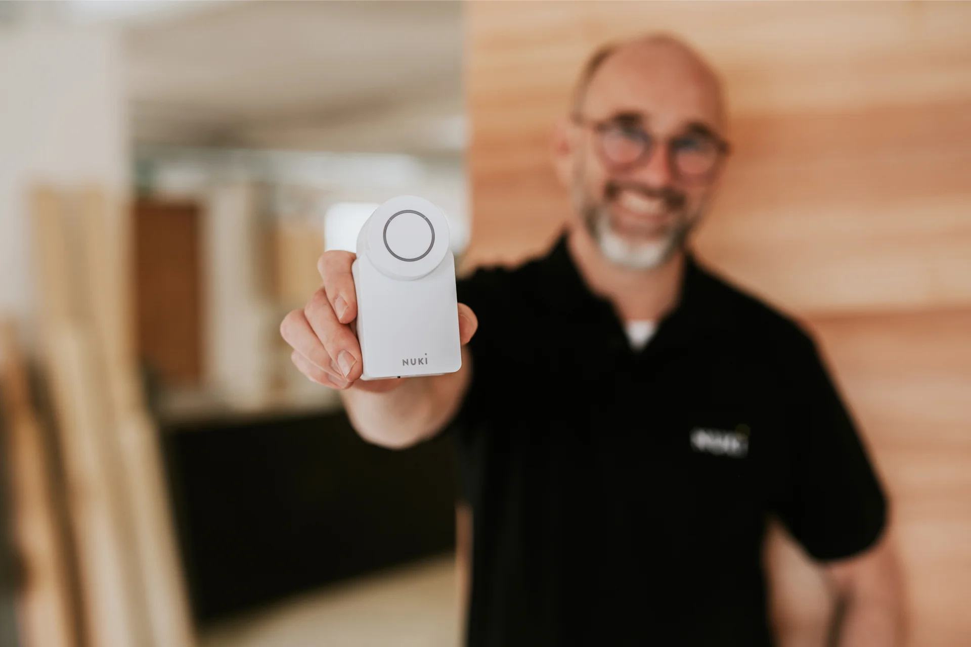 Smiling person in Nuki shirt holding the Smart Lock Go up to the camera to show the product.