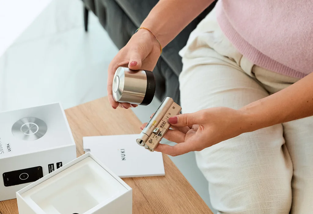 A woman sits at a table unpacking the Smart Lock Ultra and the universal cylinder.