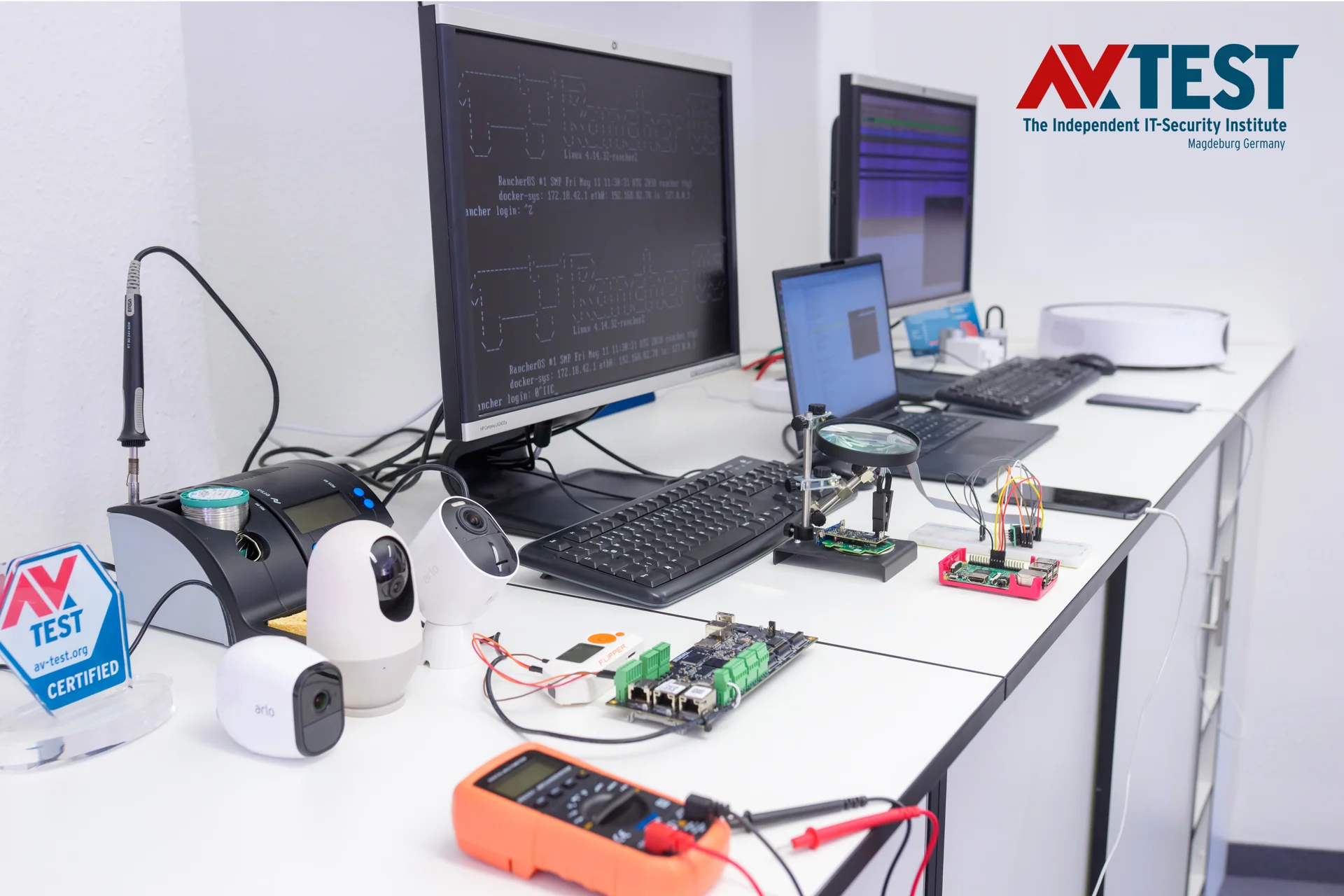 A work desk from AV-Test with three computers and many testing utensils on the table.