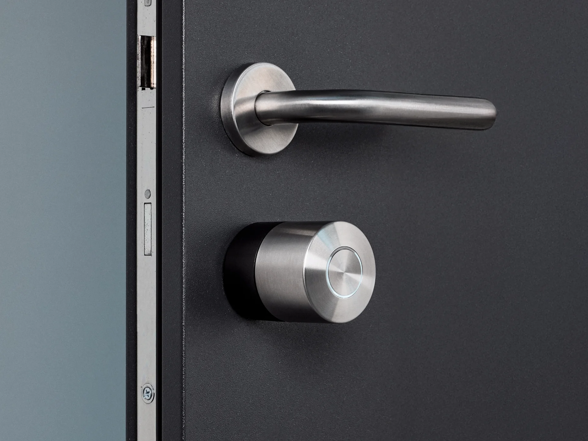 The Nuki Smart Lock Pro with the black ring mounted on a dark door with silver hardware.