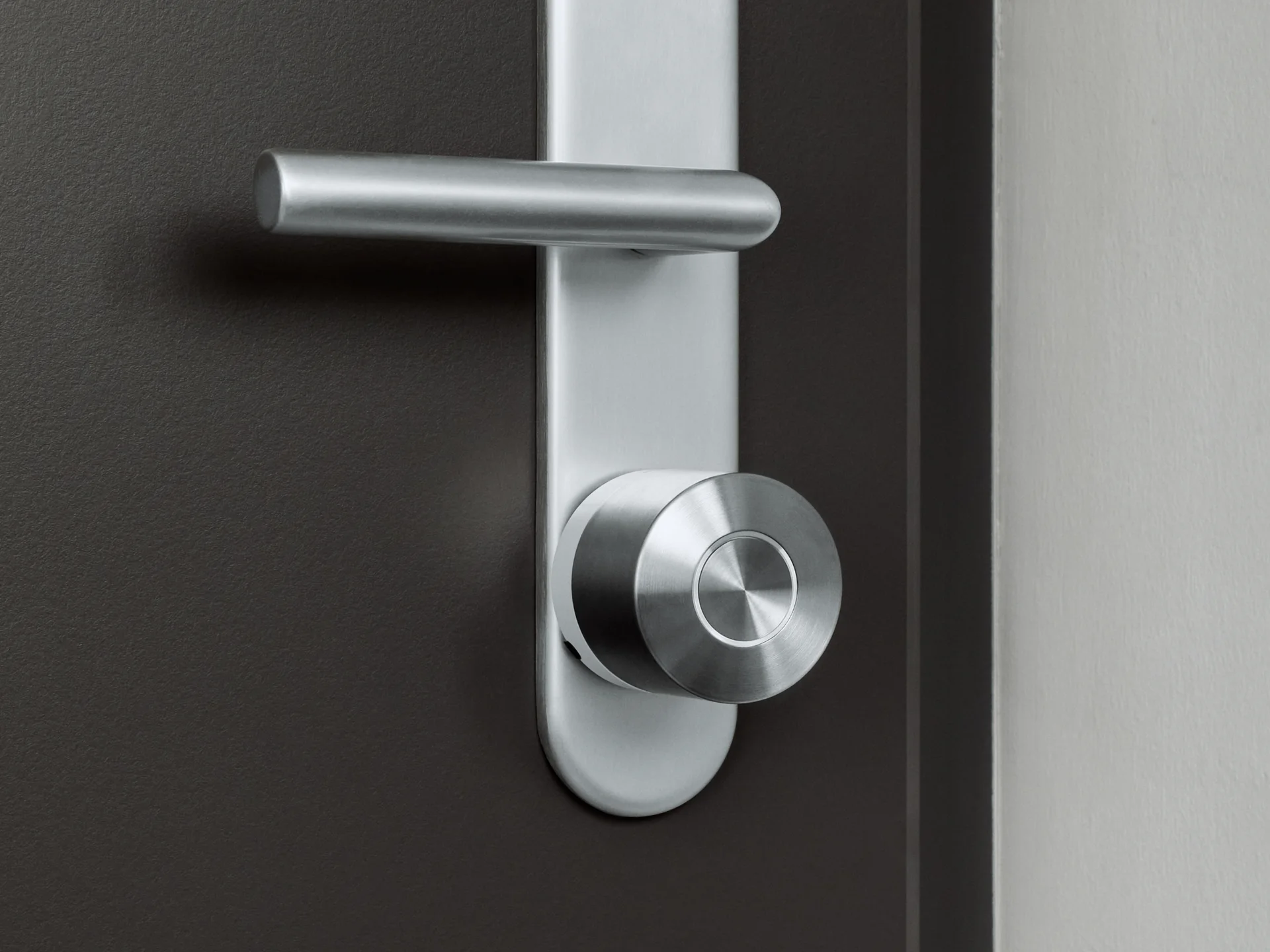 The Nuki Smart Lock Ultra with the white ring mounted on a dark door with silver hardware.