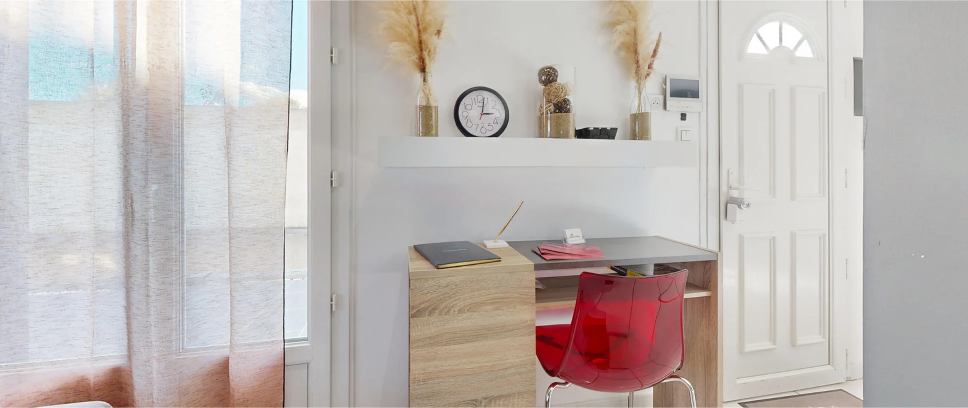 The inside of an appartment with a big window, a desk and neutral, modern interior design.