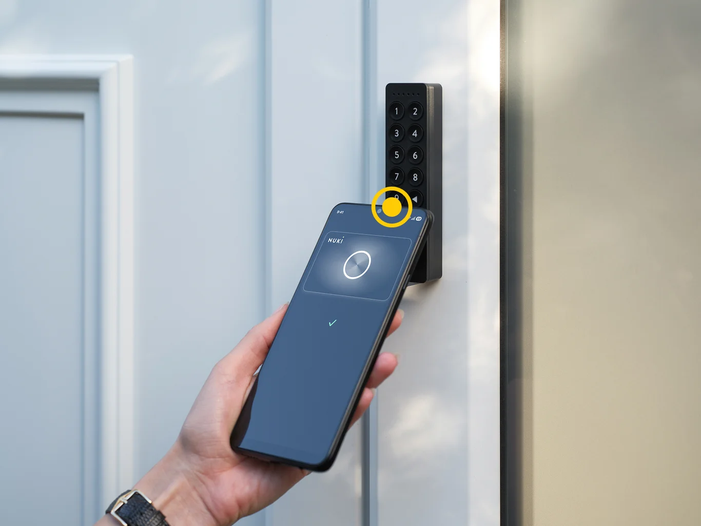 Smartphone taps to Nuki Keypad 2 NFC to open an entrance door using Tap to Unlock via NFC