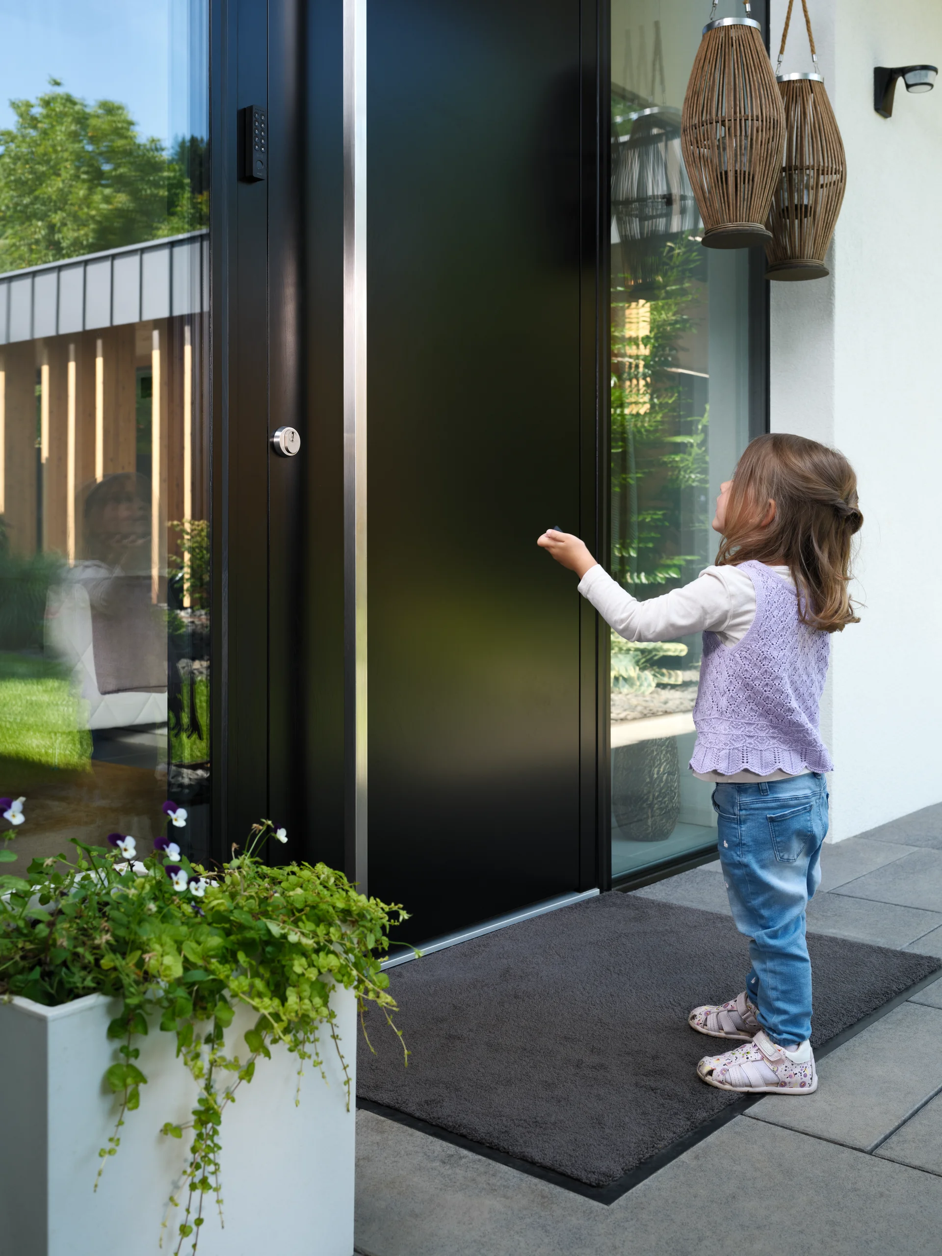 Girl standing in front of the front door pointing a fob at the door.