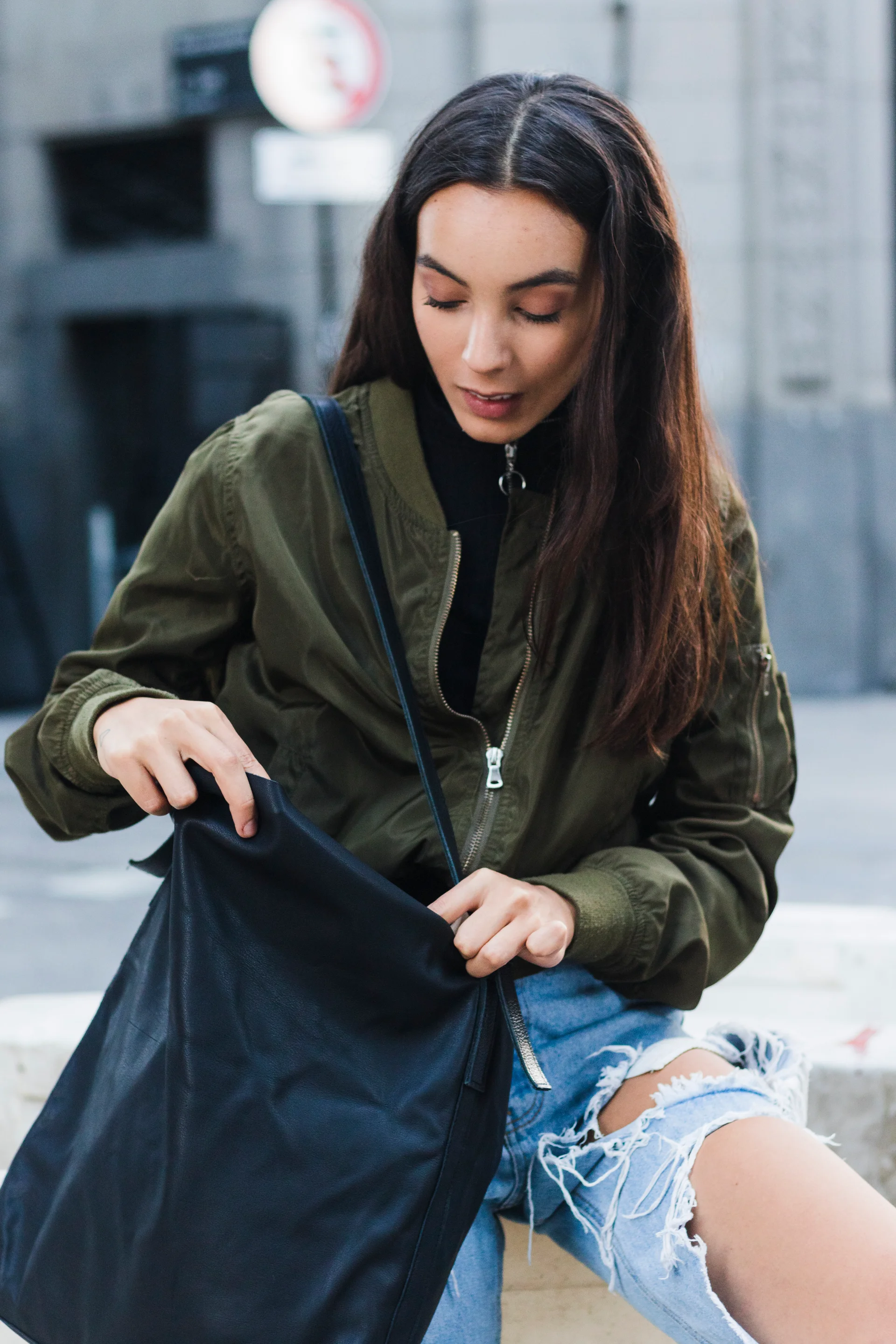 Young woman in the city searching through her bag.