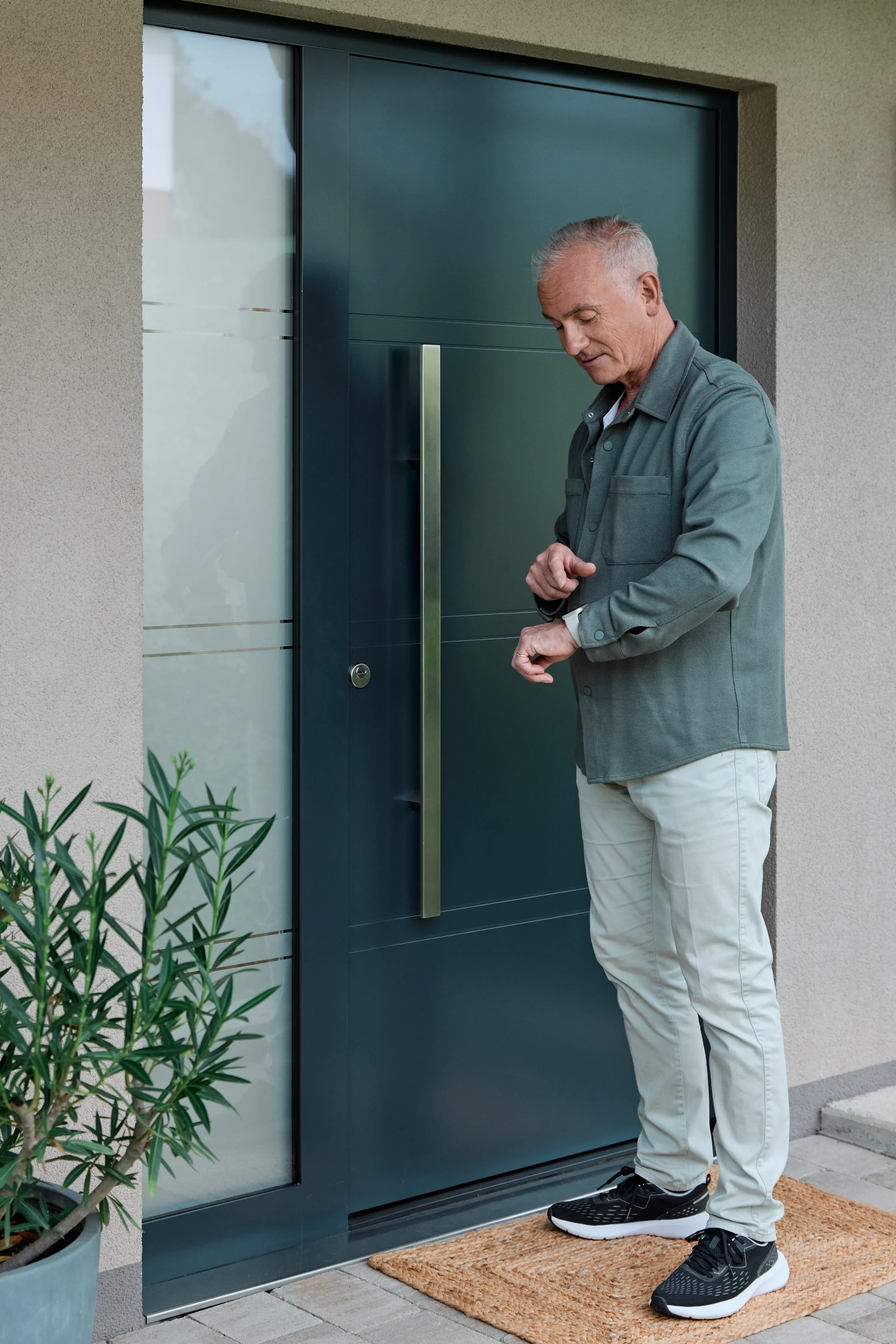 Man outside the front door looking at his smart watch.